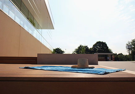 WPC Barfußdielen auf einer Terrasse eines Freibads mit Handtuch und Hut