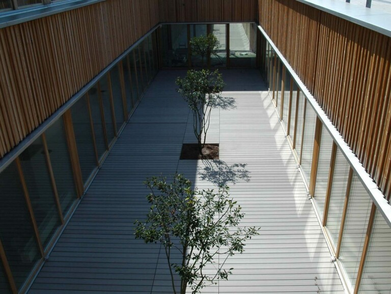 Innenhof mit WPC Terrassendielen und Holzfassade an einer Schule