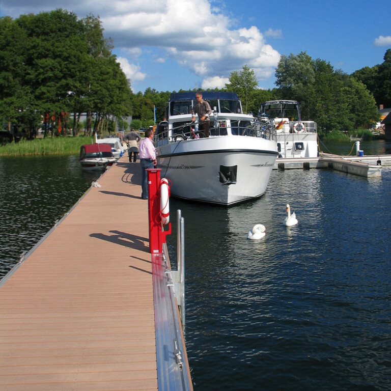 Blick auf Bootssteg mit Massivdielen in hellbraun als Belag für die Bootsstege der Marina Tor zur Müritz bei Sonnenschein