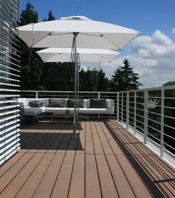 MYDECK Bodenbelag auf großem Balkon mit weißen Sonneschirmen, Outdoorsofa bei Sonnenschein