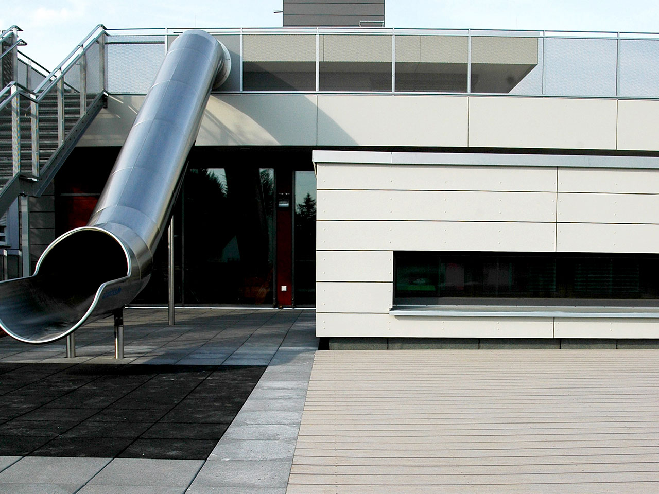 Kita mit Rutsche, modernem Energiegebäude und Terrasse aus nachhaltigen Dielen aus WPC