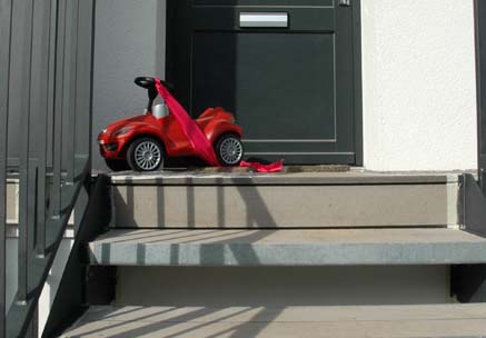 Treppenstufen mit WPC Außendielen belegt und rotem Bobbycar vor der Haustür