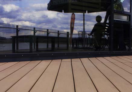 Terrassendielen aus hellbraunem WPC mit Blick auf Glasfassade mit Himmelspiegelung