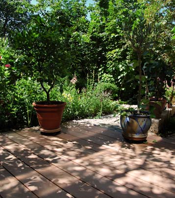 Balkon mit WPC Terrassenholz bei Sonneschein mit Blätterschatten und Bepflanzung im Hintergrund