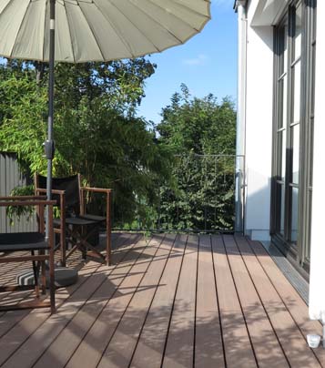Balkongestaltung mit Sitzmöglichkeit, asiatischem Sonnenschirm und Blick in die Natur