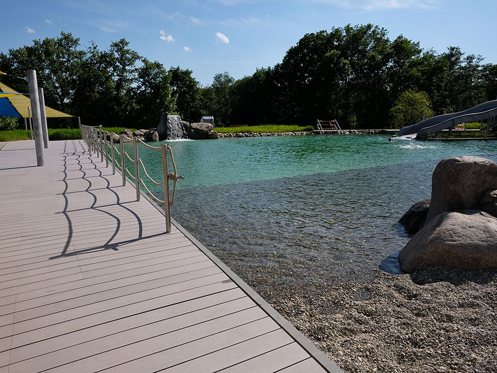 Wunderschönes Naturbad in Schwalbach mit Badestegen und Liegeflächen aus grauen MYDECK WPC DIelen