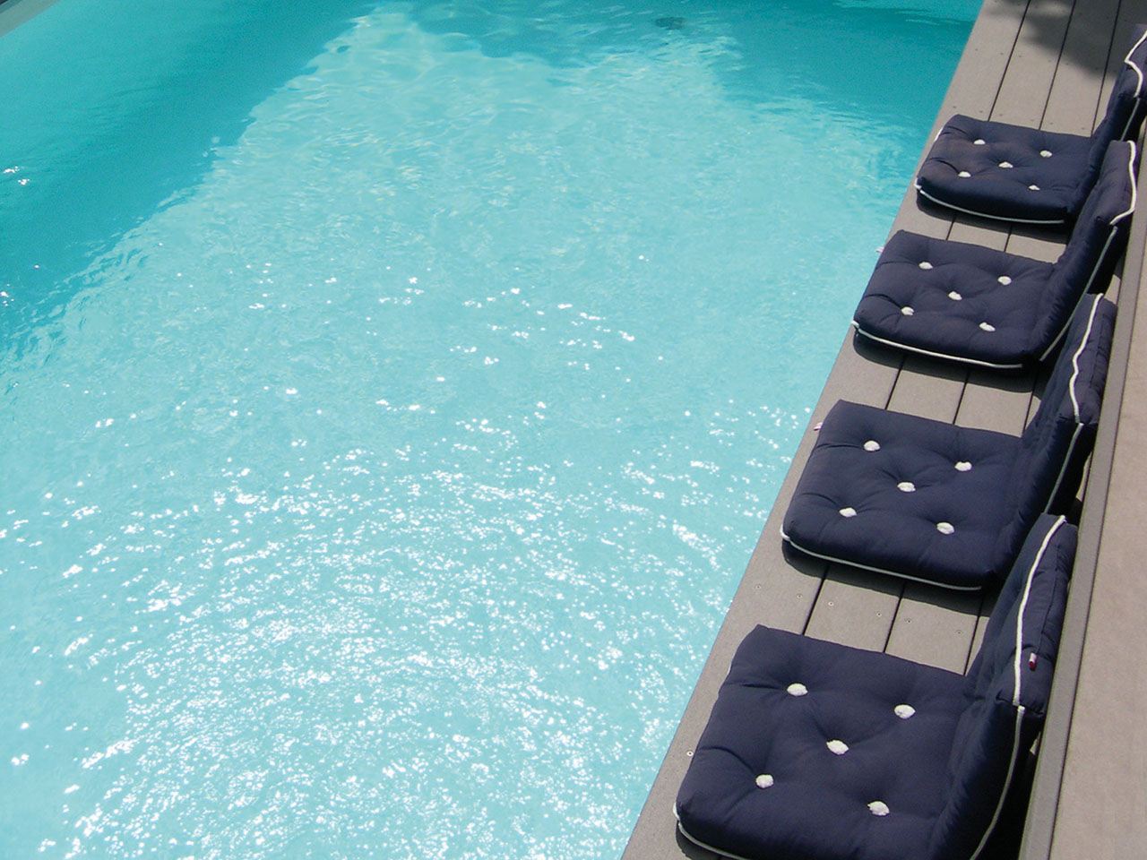Poolumrandung mit WPC Barfußdielen in grau und Teilansicht des Pools