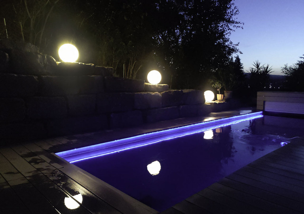 Schwimmbad bei Nacht mit nassen WPC Terrassendielen
