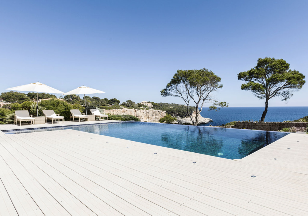 Großzügiges Schwimmbad mit hellen WPC Terrassendielen im mediterranem Ambiente