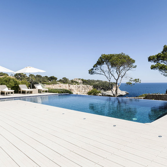 Großzügiges Schwimmbad mit hellen WPC Terrassendielen im mediterranem Ambiente