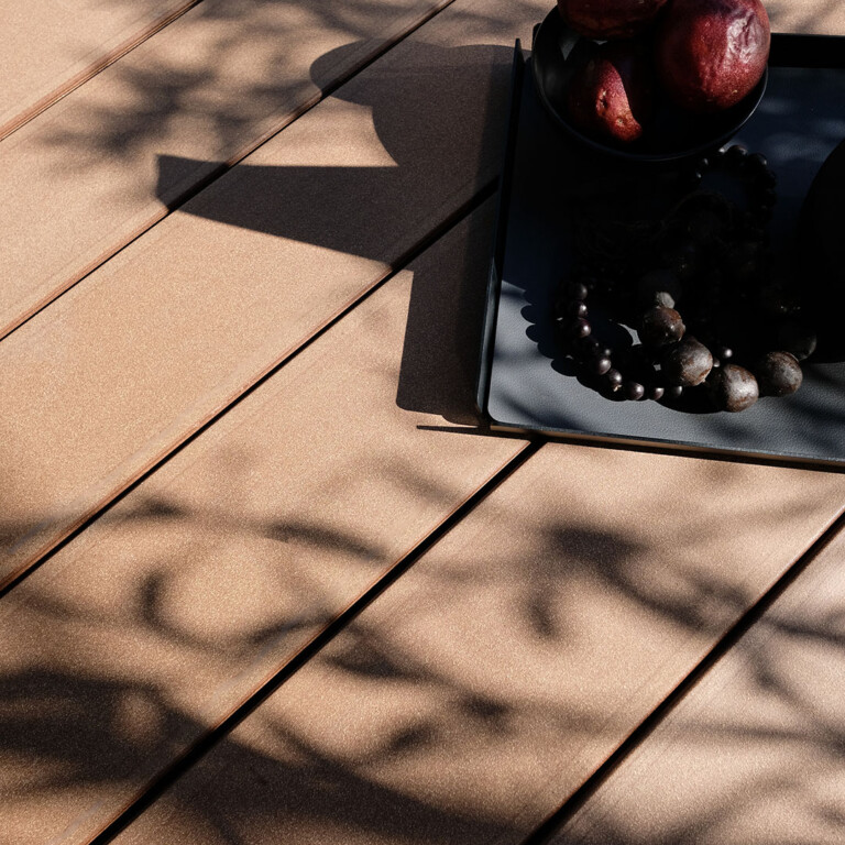 Dunkelbrauner WPC Terrassenbelag bei Sonnenschein mit Schatten einer Pflanze