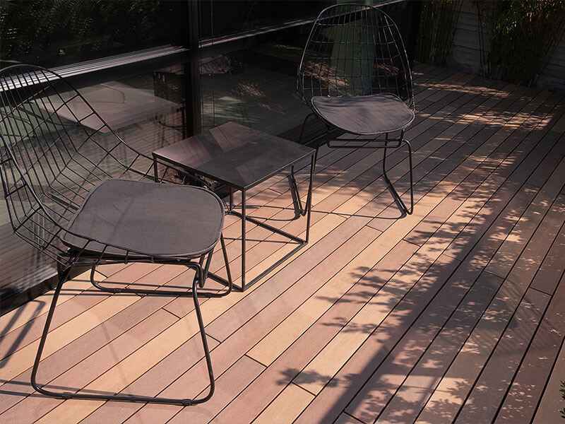 Terrassenbretter in unterschiedlichen brauntönen auf Terrasse mit Sitzgelegenheit