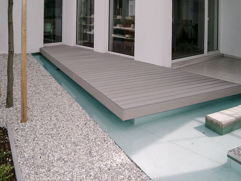 Graue WPC Terrassenbretter auf Terrasse die Über Pool, bzw. Wasserfläche schwebt