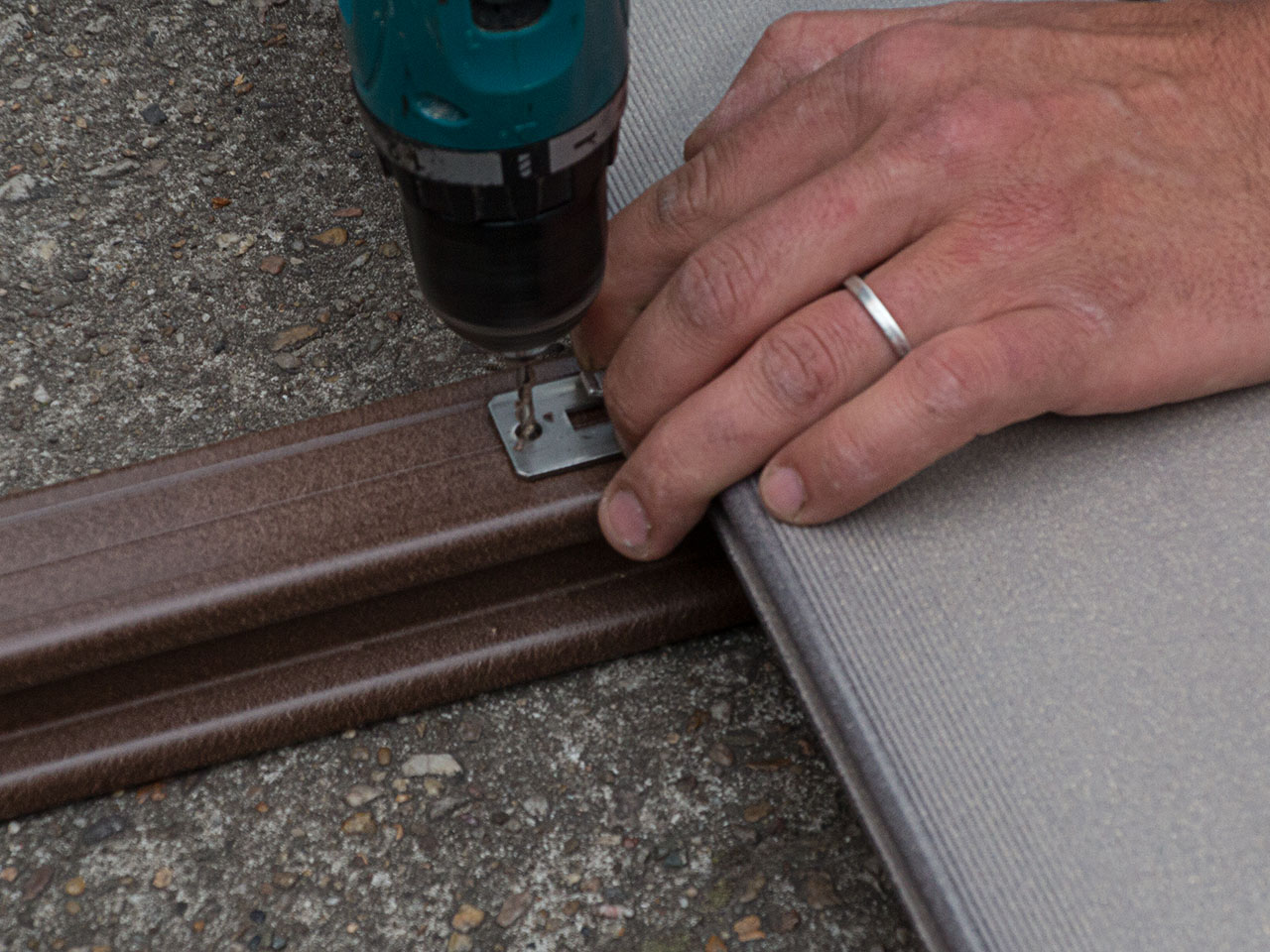 Verlegung der massiven WPC Dielen mit Nut, Detailaufnahme des Festschrauben des Clips