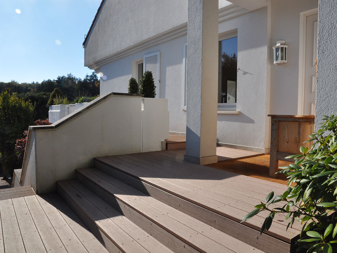 WPC Terrasse mit Stufen vor moderner Villa bei Sonnenschein