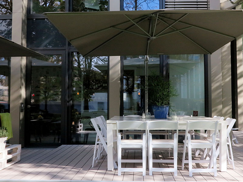 Aussendielen aus grauem WPC auf der Terrasse eines modernen Cafés mit weißen Möbeln