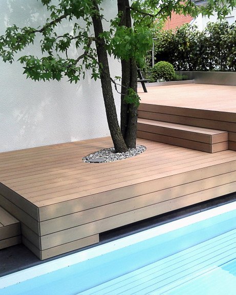 Bildschöne Terrasse mit braunen WPC Dielen und mit mehreren Stufen und Ebenen vor Pool und Haus