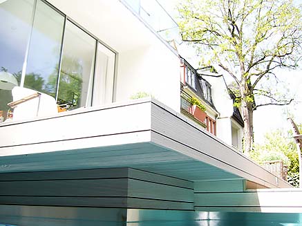Blick vom Pool auf stufenförmig angeordnete Poolumrandung aus WPC Terrassendielen