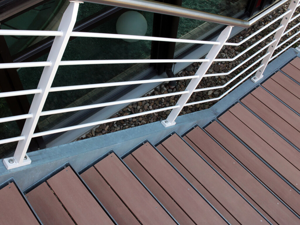 Treppe aus braunen WPC Terrassendielen und einer Einfassung und Geländer aus Stahl