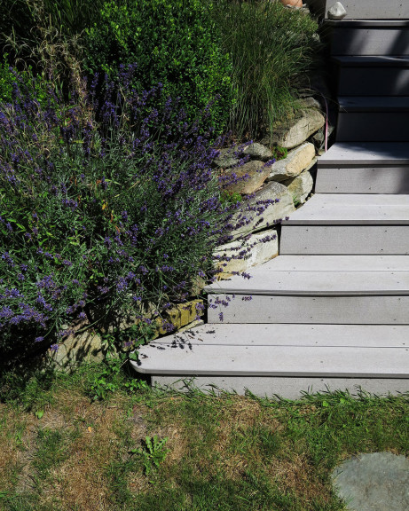 Stufen mit grauen WPC Terrassendielen massiv um Natursteinmauer