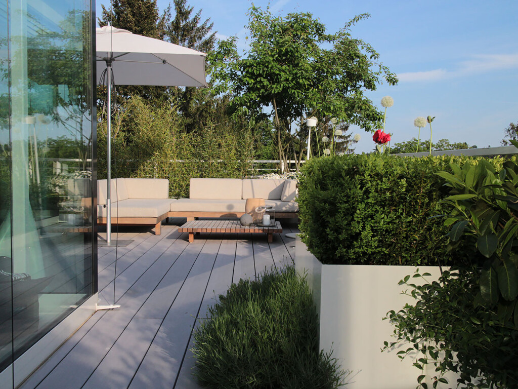 Sonniger Sitzplatz auf WPC Terrasse mit großzügiger Begrünung