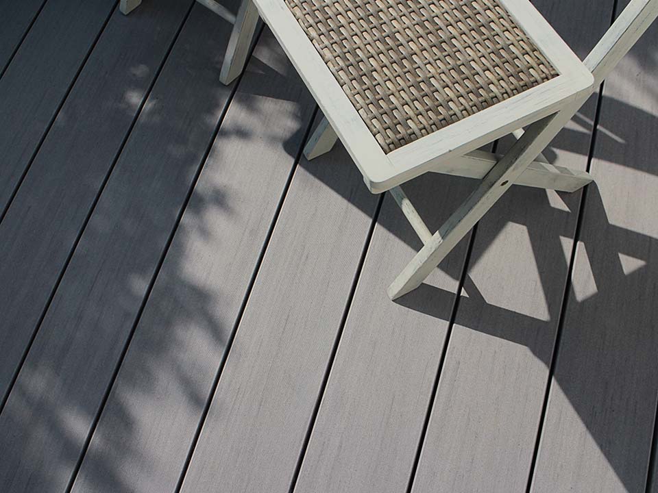 Aufsicht auf die graue Terrassendiele der Pure Kollektion von MYDECK mit Schattenwurf von Stühlen und Pflanzen.