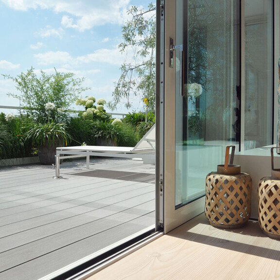 Die moderne Design Terrasse mit den grauen WPC Terrassendielen harmoniert mit dem modernen Interieurdesign