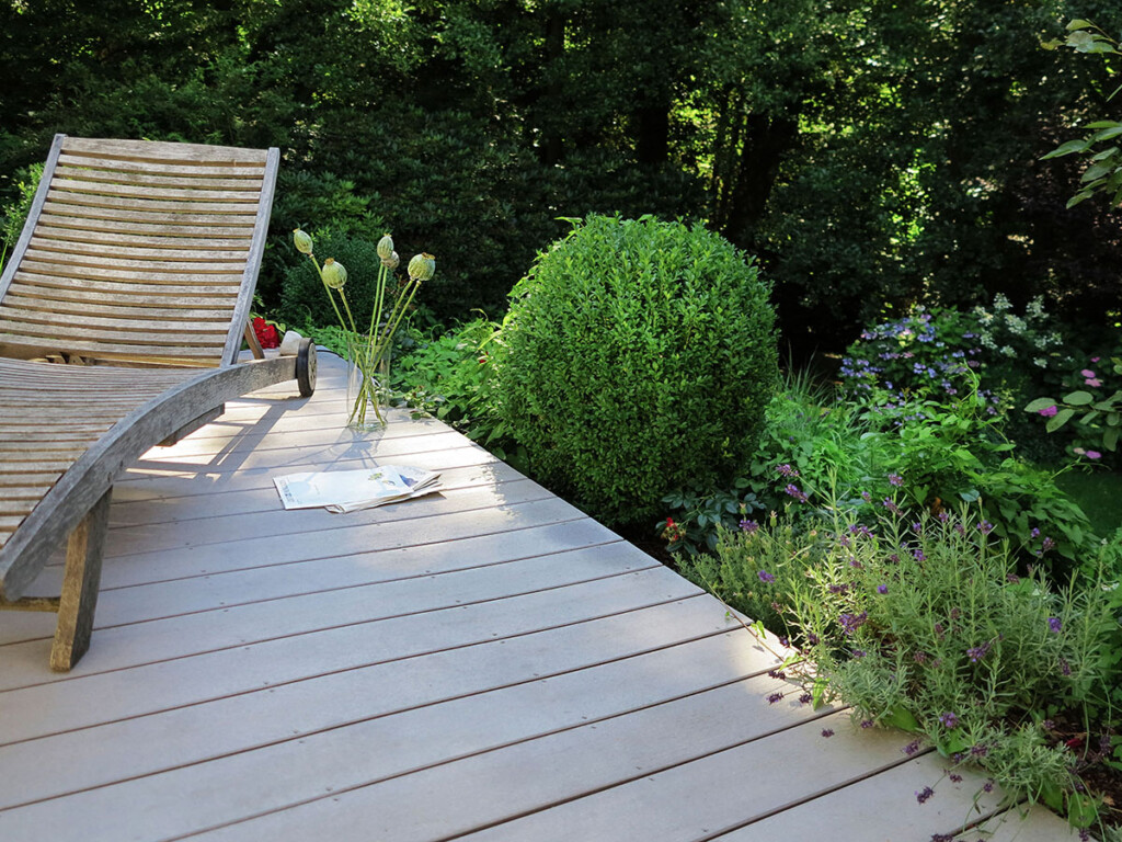 Graue WPC Massivdielen auf einer Terrasse mit angrenzender Bepflanzung im Cottage Garden Stil