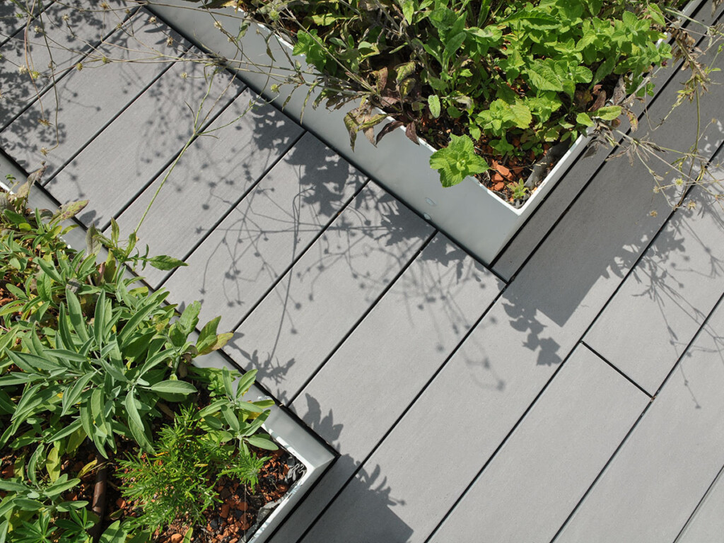 Die grauen WPC Dielen sind bei dieser modernen Terrassengestaltung um die Hochbeete herum verlegt