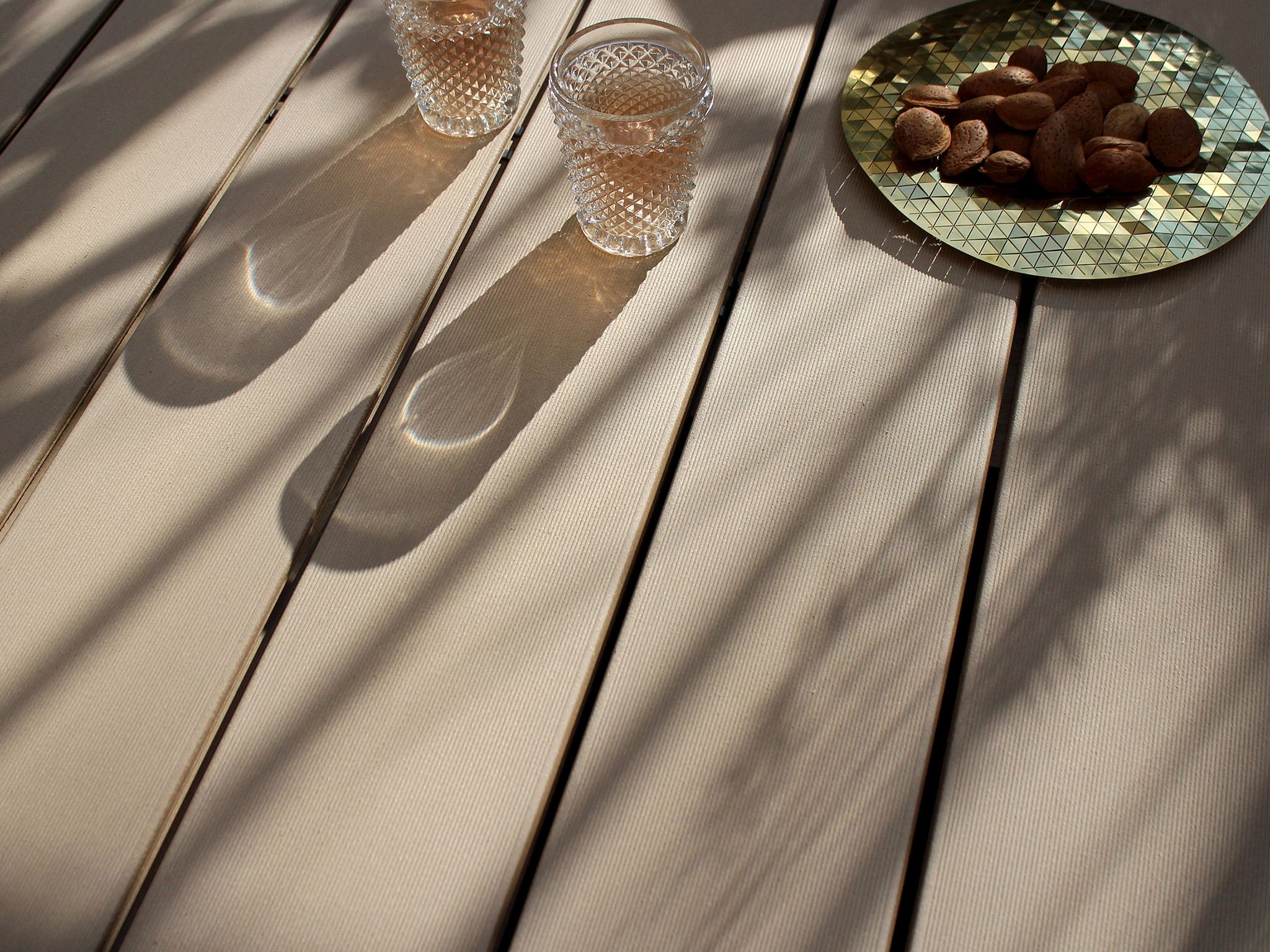Bildschönes Detailbild von hellbraunen WPC Terrassendielen bei Sonnenschein