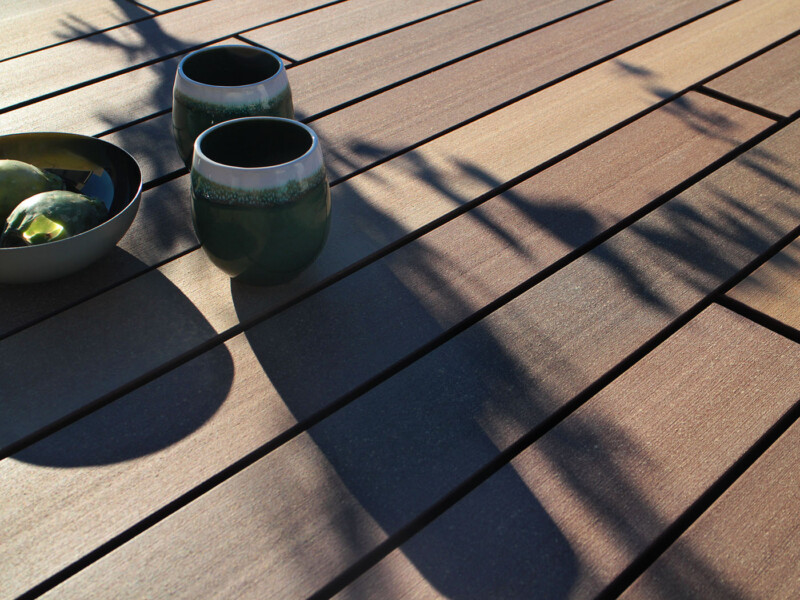 Wood plastic composite Terrassenbelag bei Sonnenschein mit Frühstücksgeschirr
