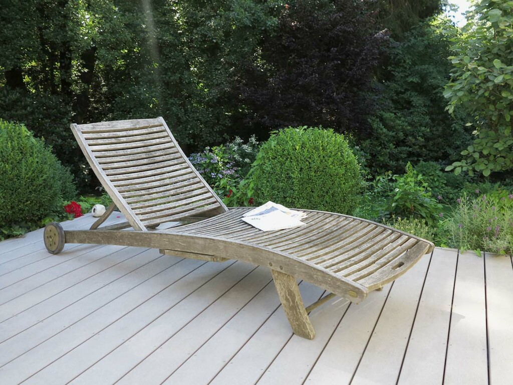 Graue WPC Terrasse mit wettergegerbtem Liegestuhl aus Holz