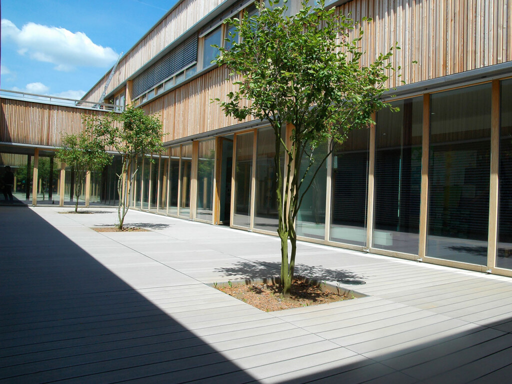 Die grauen WPC Dielen in dem Innenhof der Schule sind splitterfrei und ergänzen ideal die moderne Architektur.