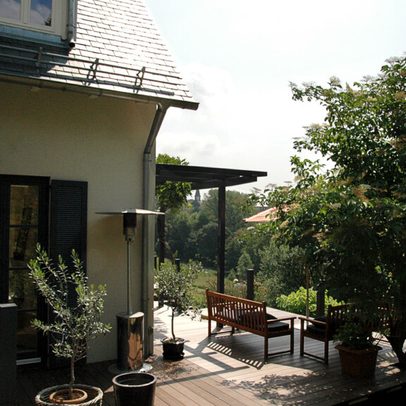 Die um das Haus herum verlegte Terrasse verläuft immer quer zur Hauswand