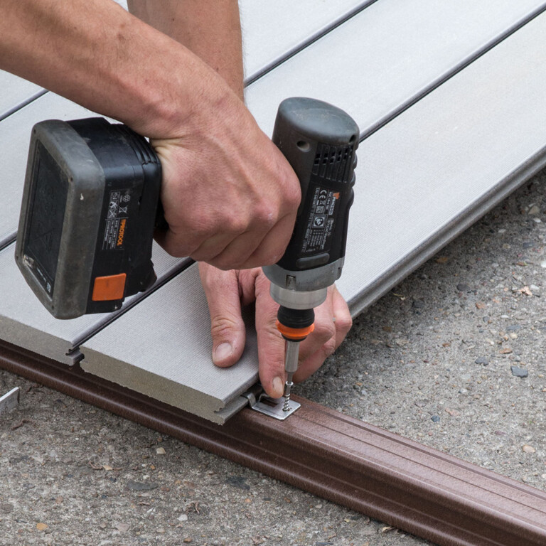 Handwerker bei der Verschraubung des zu den WPC Dielen gehörenden Clips auf der Unterkonstruktion