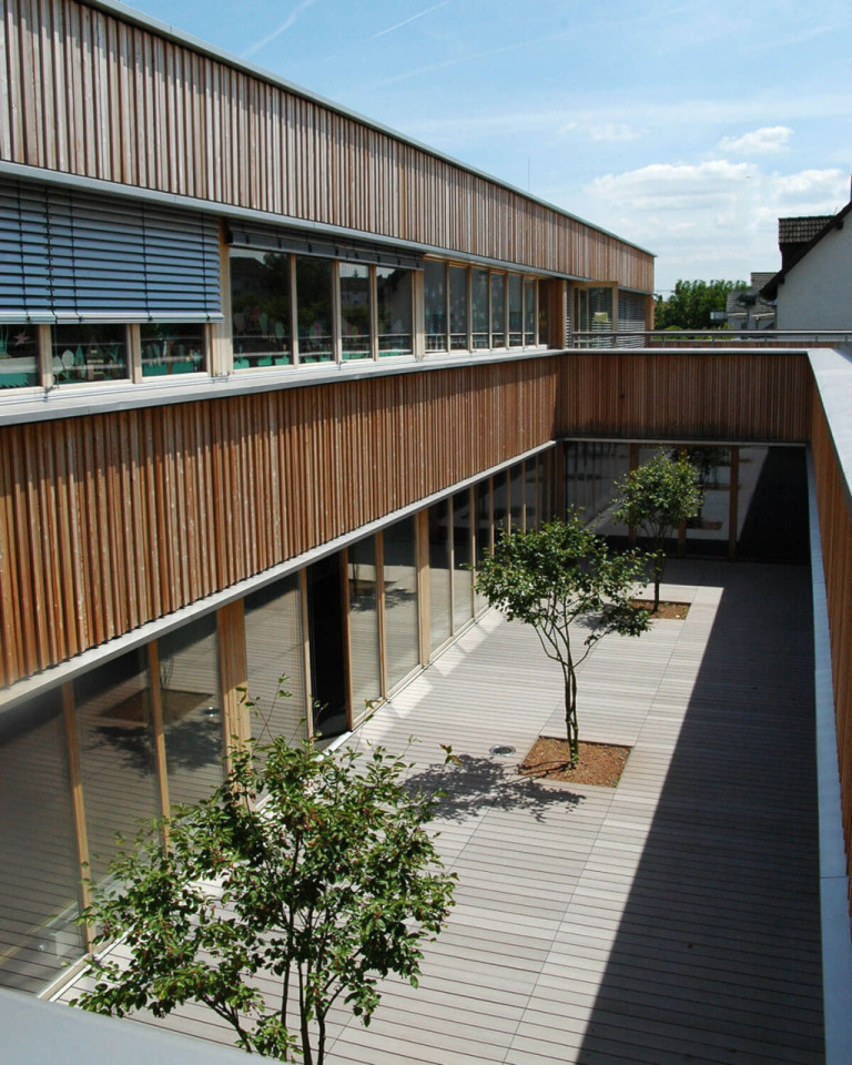 Innenhof mit grauen WPC Terrassendielen von MYDECK und Bäumen im Innenhof