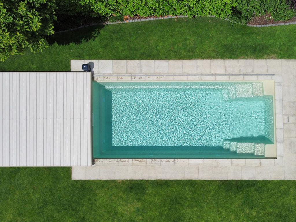 Begehbare Poolabdeckung mit hellen WPC Barfußdielen im Garten, Poolumrandung aus Stein