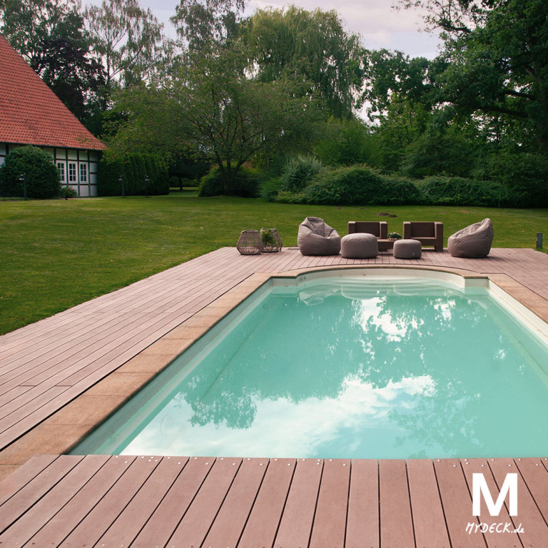 Großer geschwungener Pool mit Liegefläche und braunen WPC Massivdielen im Garten