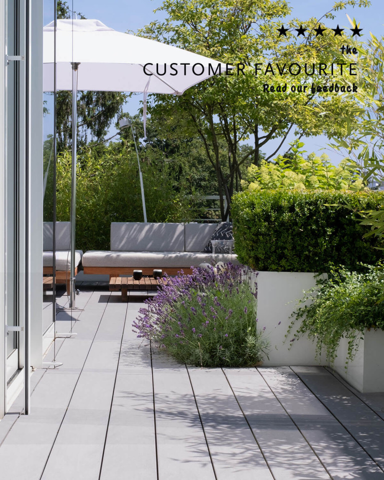 Cosy seating area on terrace with grey, wide WPC decking boards and terrace design with lots of plants