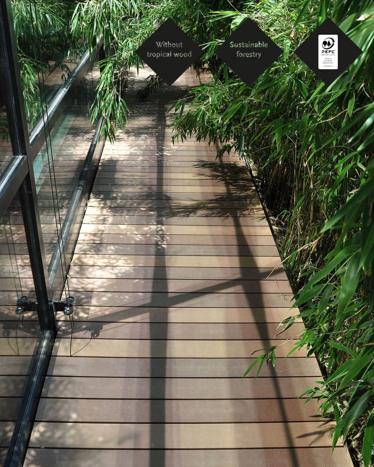 Wood-look WPC decking boards on patio walkway with side bamboo bed