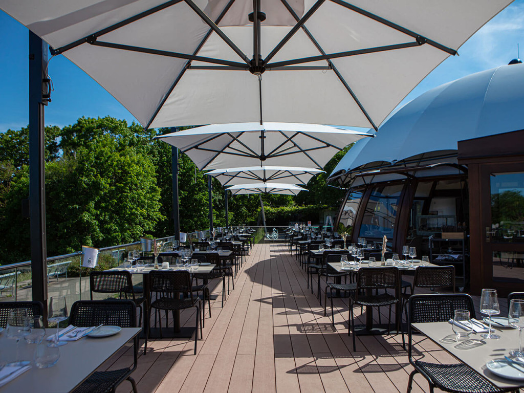 Terrasse mit hellbraunen WPC Dielen und großen Sonnenschirmen des Restaurant Bellevue Stuttgart