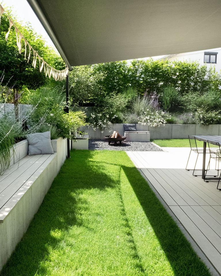 Terrasse mit hellen WPC Dielen in Garten und mt Bank, welche ebenso mit den Dielen verlegt sind