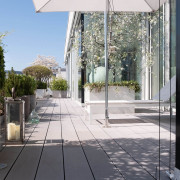 Moderne Designterrasse mit grauen breiten WPC Terrassenbelag und Sonnenliege