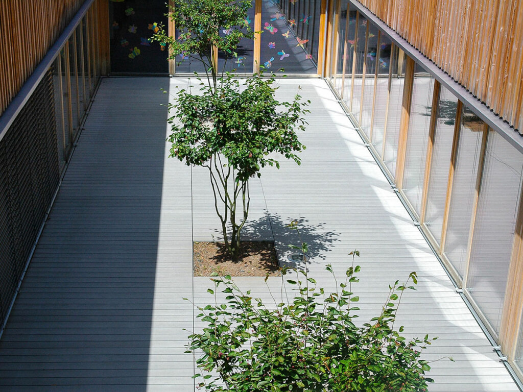Graue, nachhaltige Premium WPC Dielen in Schule, mit integrierten Beet mit Baum