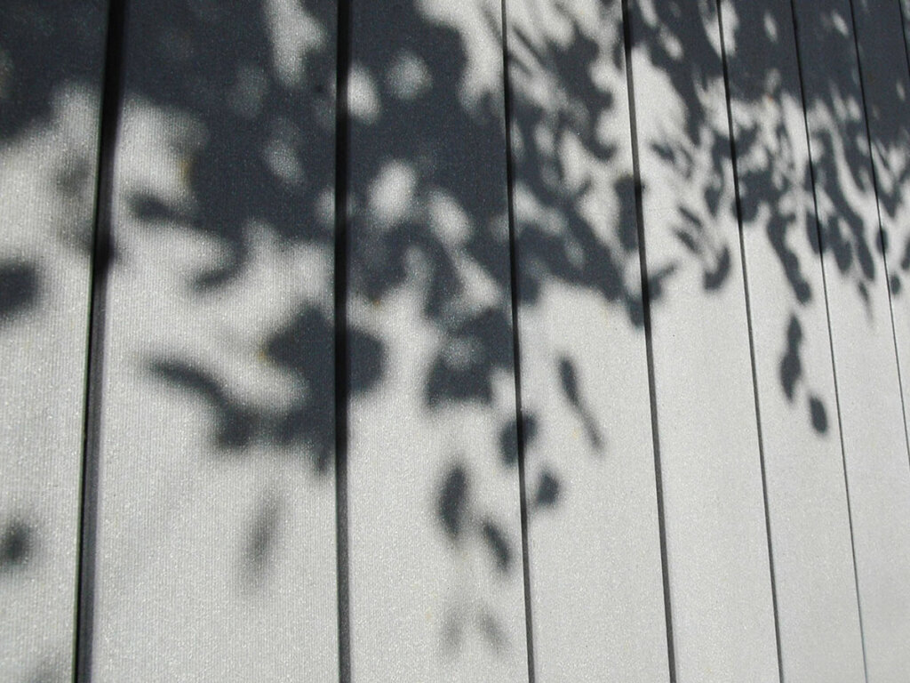 Vielfach für Design + Qualität prämiert. Detailansicht graue glatte und rutschfeste WPC Dielen mit Blätterschatten