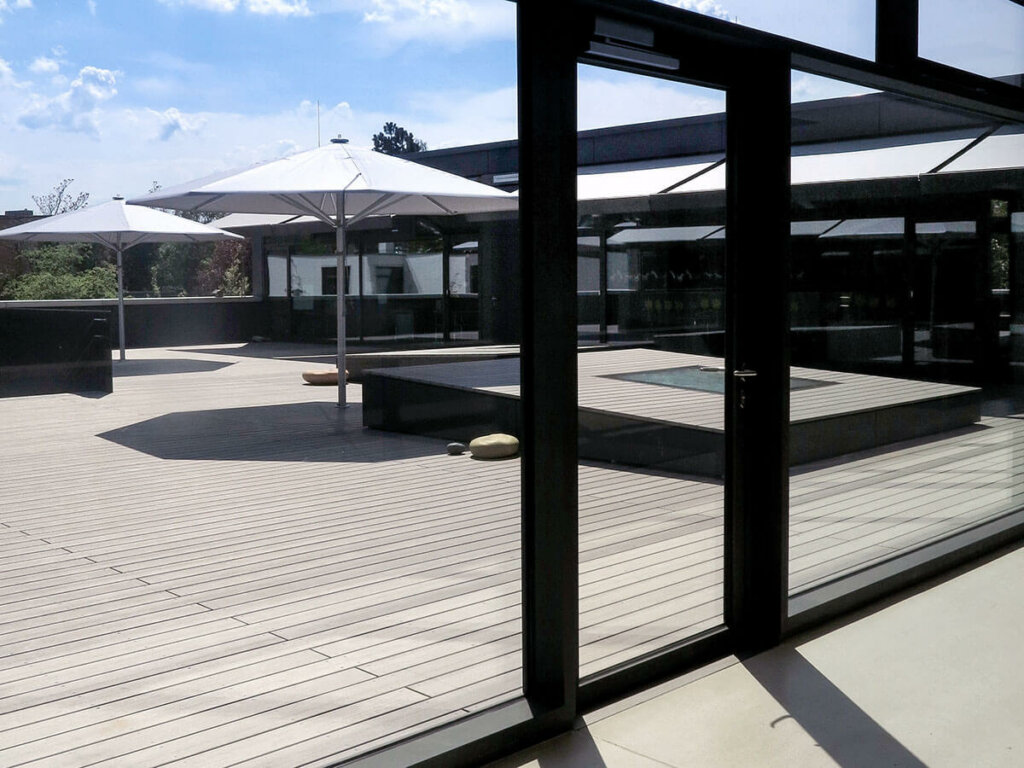 Blick durch Fenster in Innenhof einer Schule mit Terrasse mit WPC Dielen