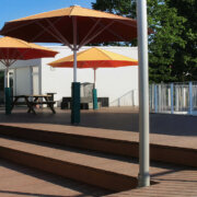 Stufenförmige Terrasse in Kita mit Premium WPC Massivdielen und großen roten Schirmen
